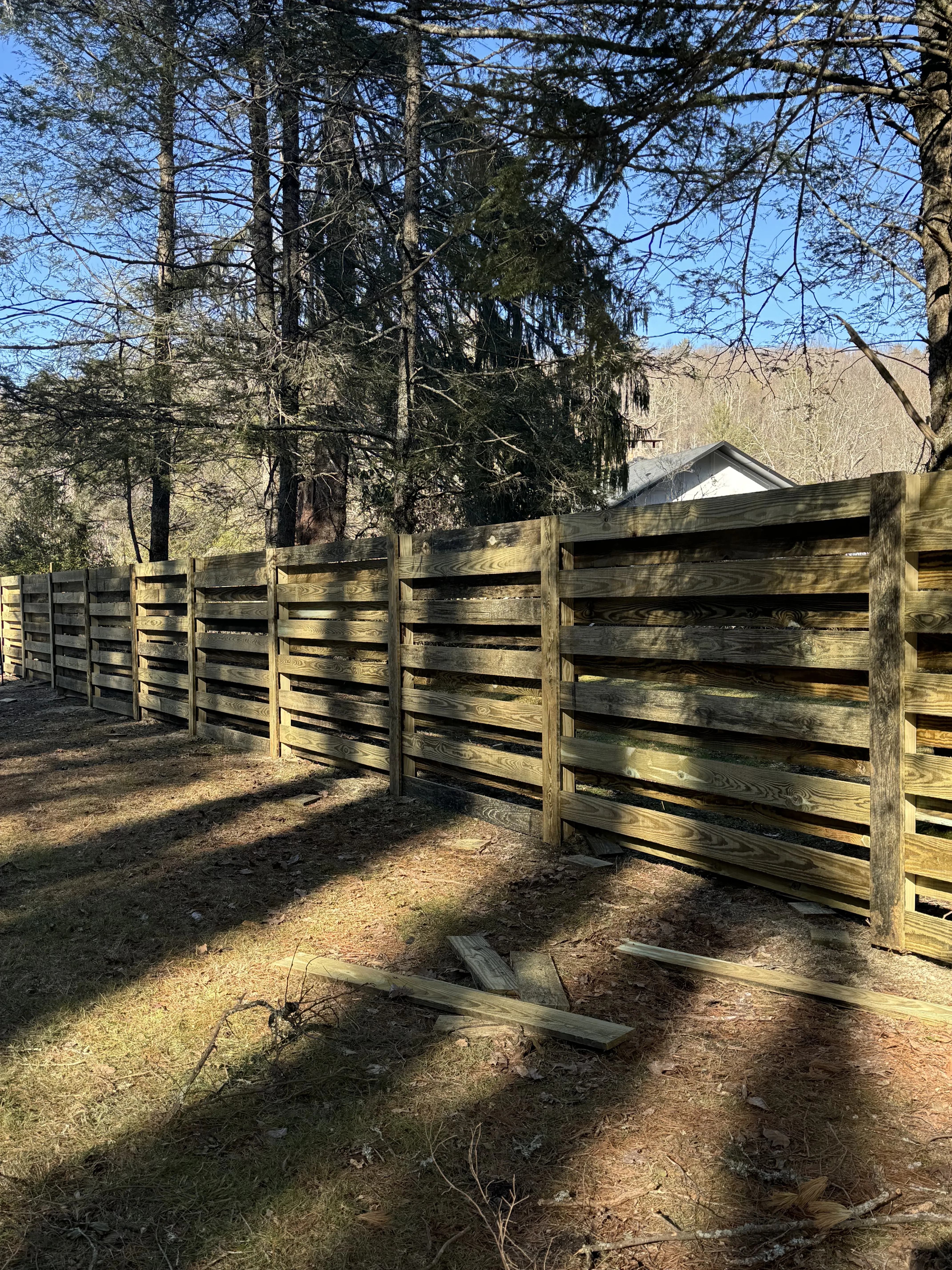 Wood shadow box privacy fence with trees